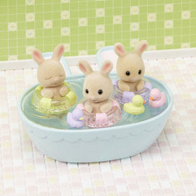 Milk rabbit triplets in bathtub with toys