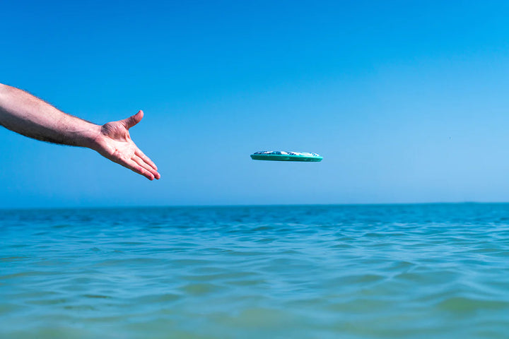 hand throwing flobo in the ocean
