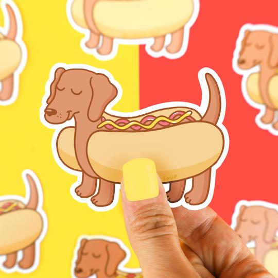 hot dog dachushund puppy dog vinyl sticker held above yellow and red background