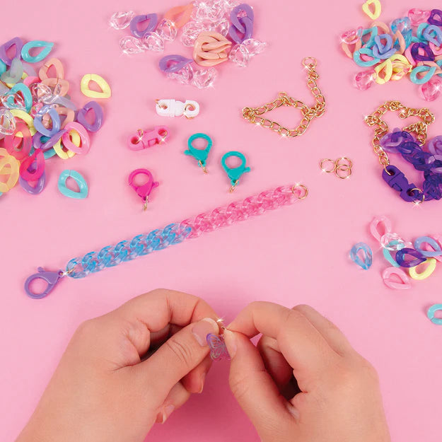 Pink Background with a display of hands completing jewelry from kit