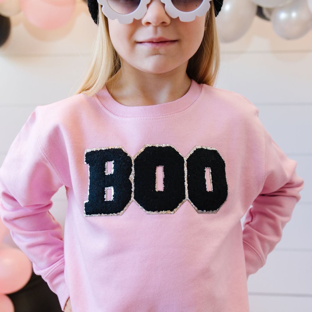 Pink sweatshirt with black BOO patch on young girl