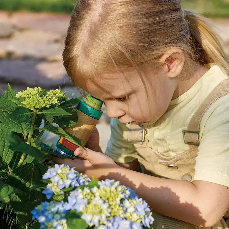 little girl using miscroscope with flowers