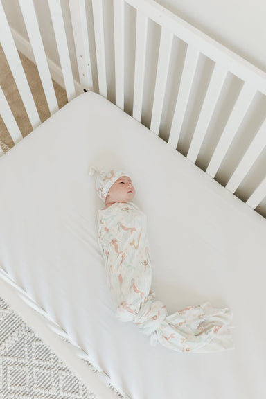 baby in crib wearing blanket and matching hat