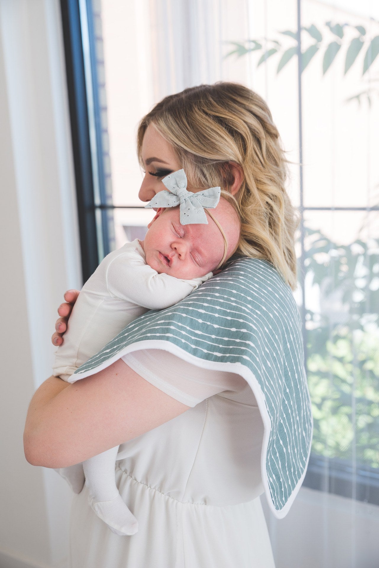baby resting on womans shoulder laying on blue burp cloth