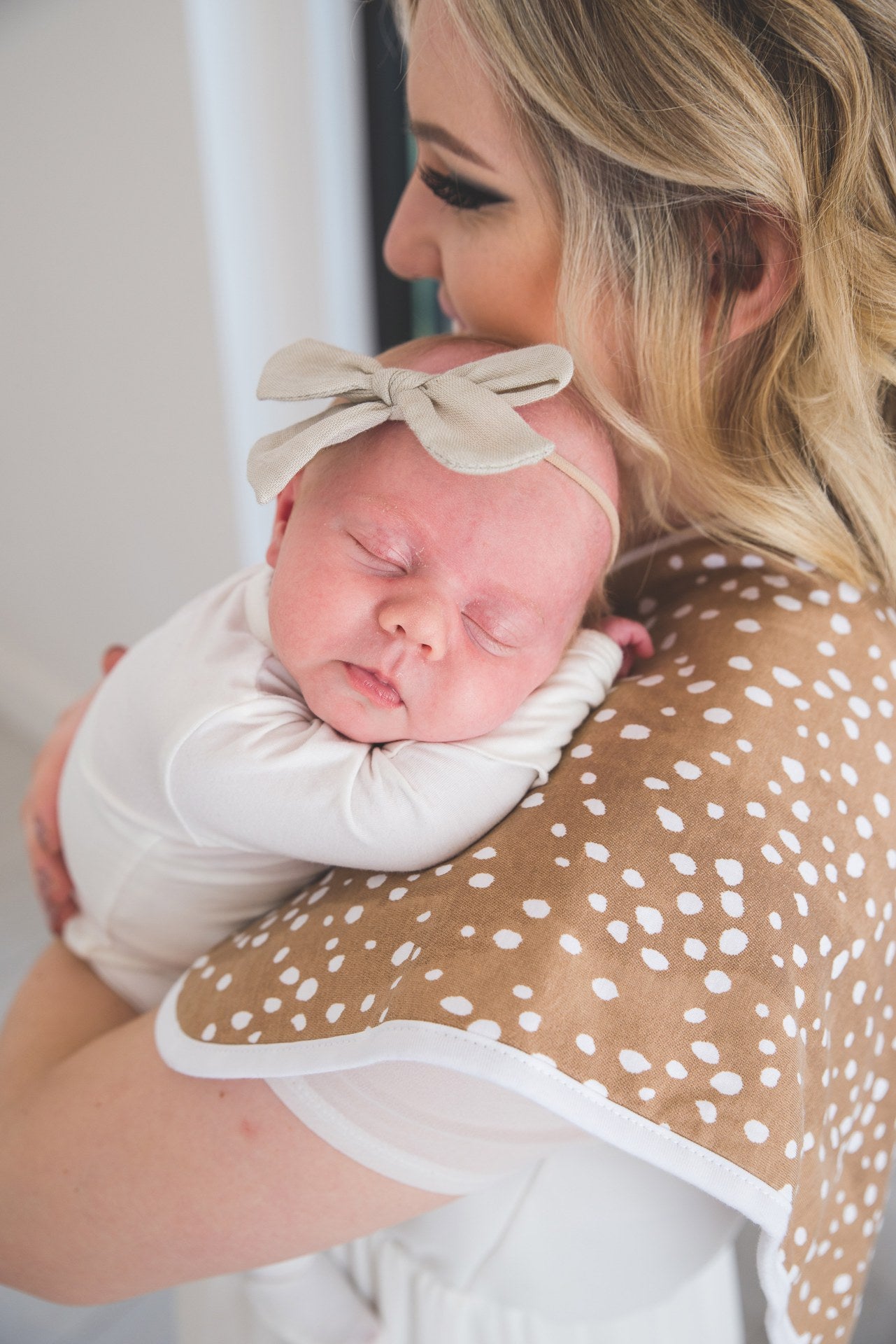 baby laying on womans shoulder resting on brown burp cloth
