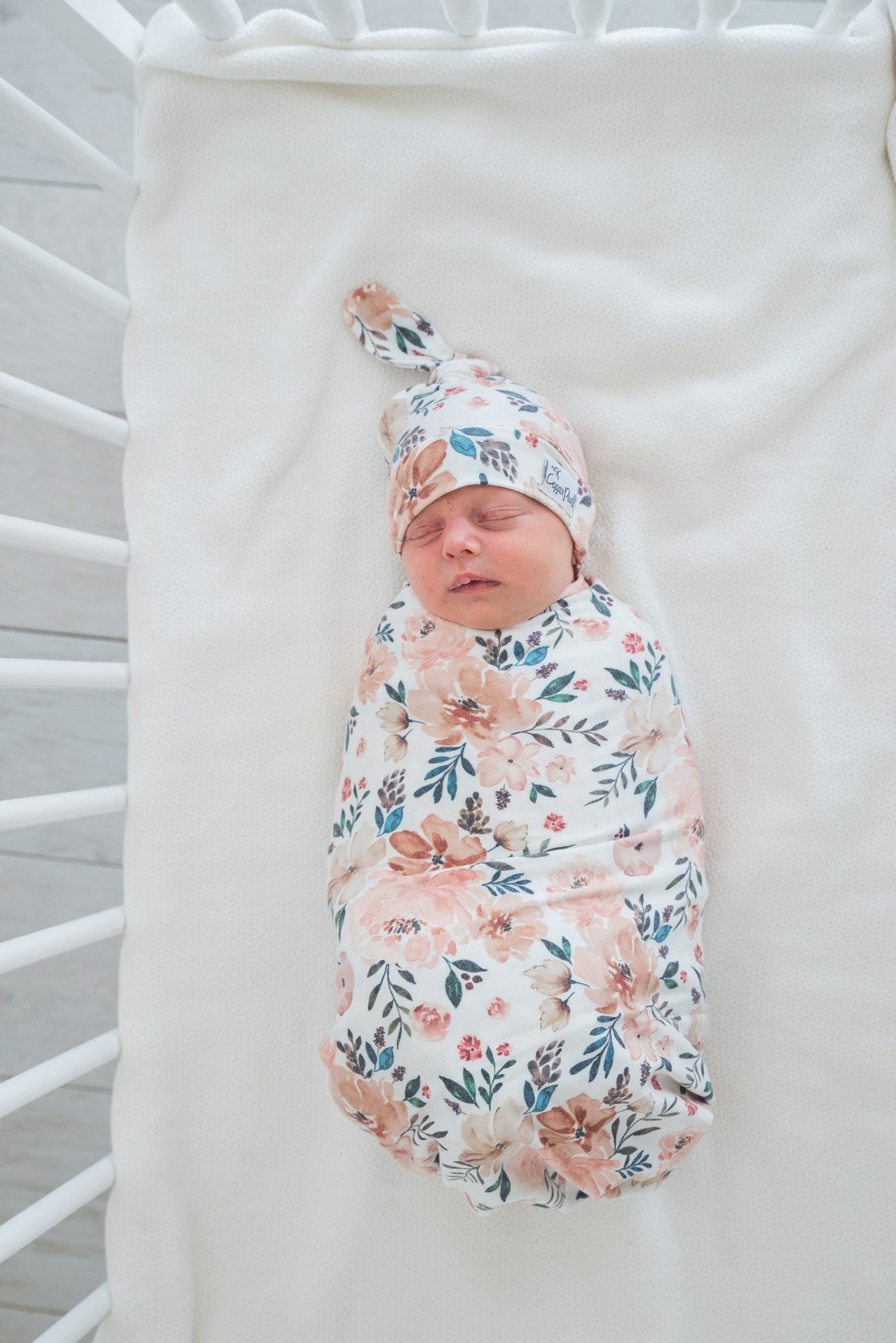 baby wearing top knot hat and wrapped in matching blanket