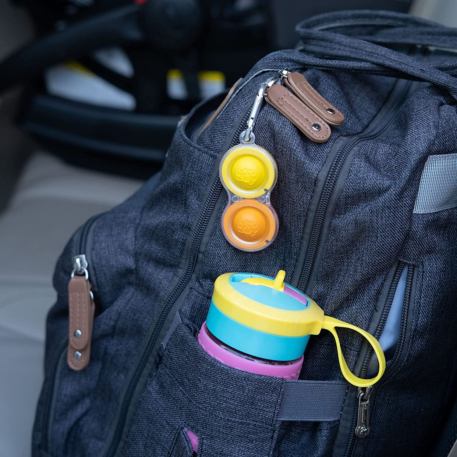 yello and orange simpl dimpl hooked onto backpack as keychain