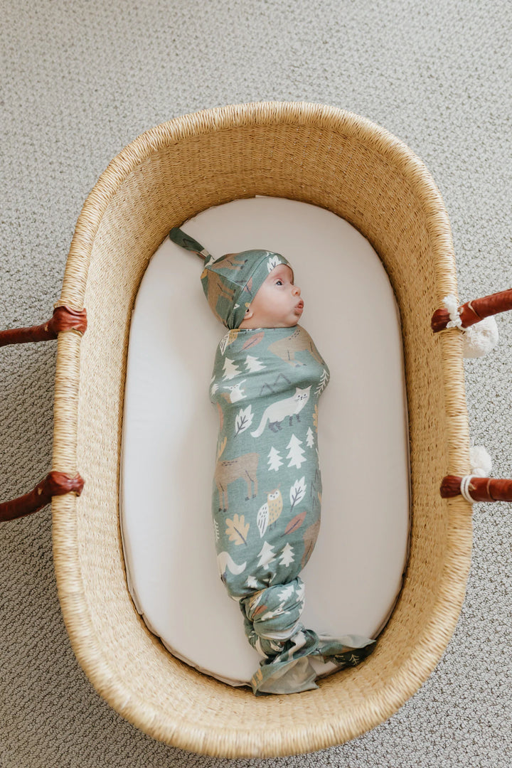 baby in basket wrapped in blanket and matching hat